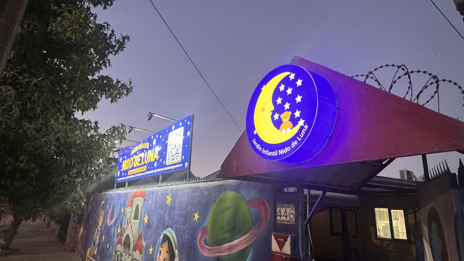 El letrero de la luna encendido de noche sobre la entrada del jardín