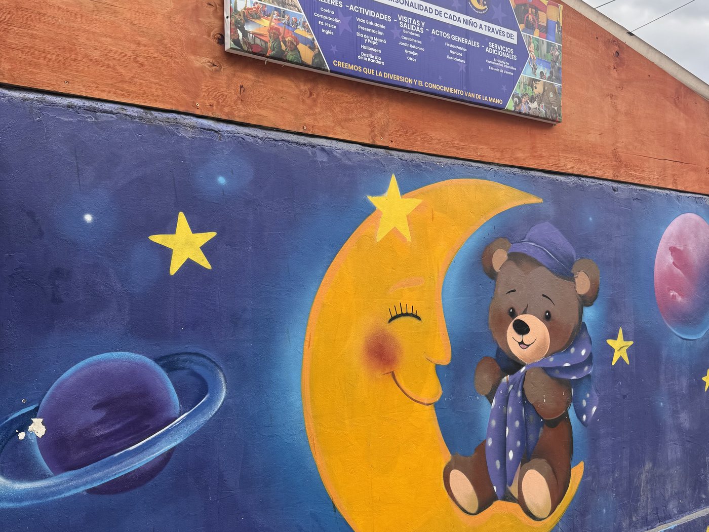 Mural de la luna con un osito en pijama entre estrellas y planetas