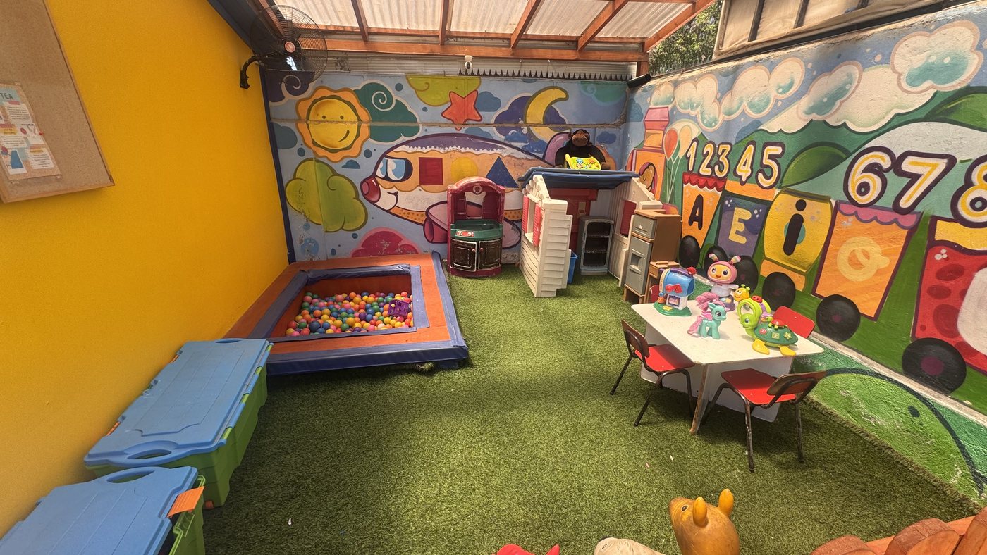 Sala de juegos con pasto sintético, pozo de pelotas y murales de colores